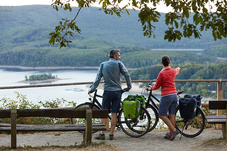 Ausflug mit dem Fahrrad Eine Frau und ein Mann mit Fahrrad in schöner Flusslandschaft